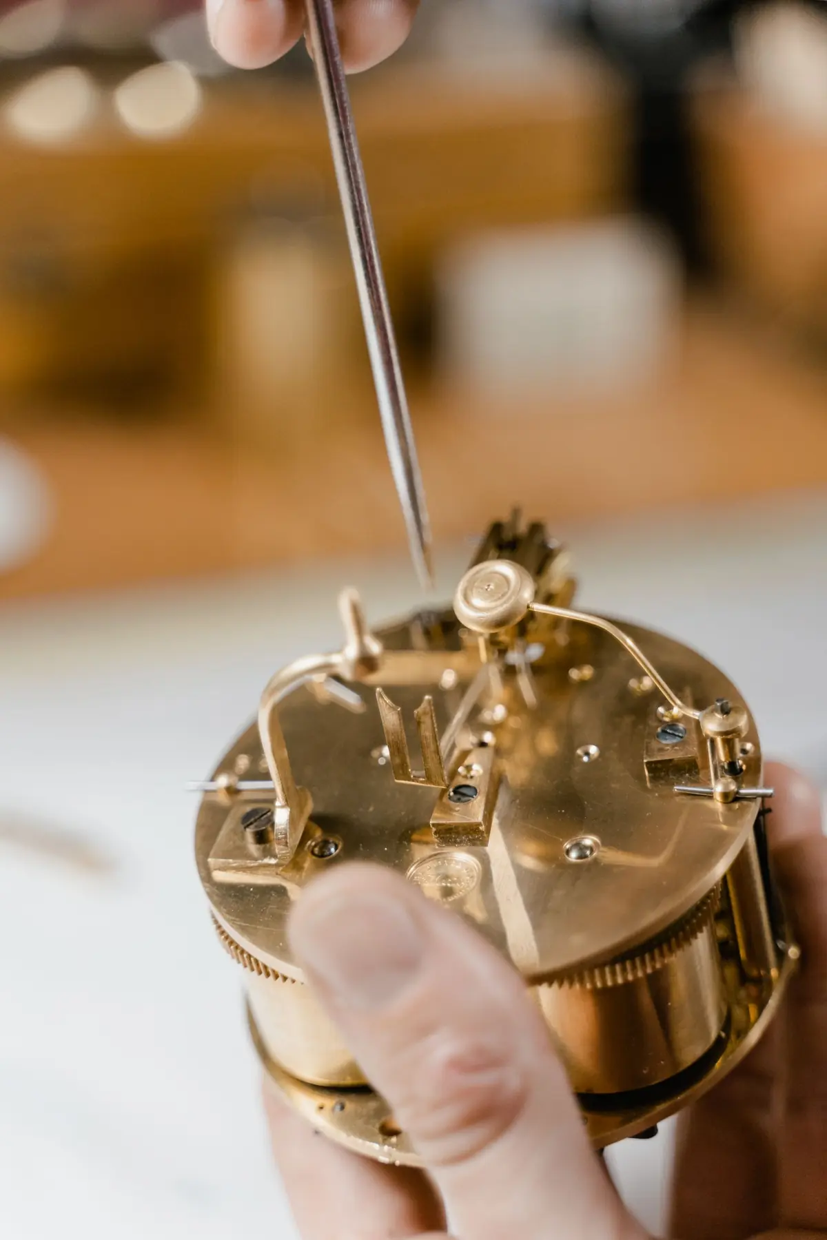 Handen die zorgvuldig aan een uurwerkmechanisme werken